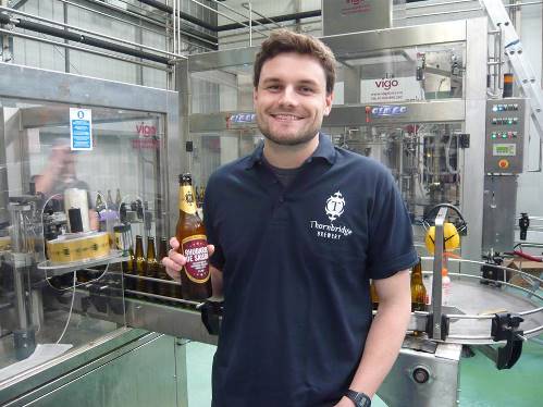 Photograph of Will Alston with a bottle of Rhubarbe de Saison